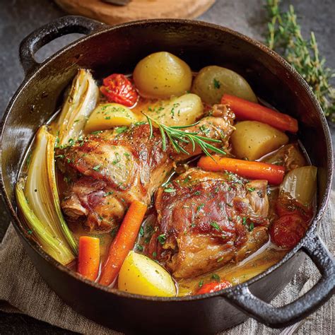 Une cocotte avec des morceaux de coq dorés et des légumes