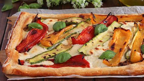 Une variété de charcuteries italiennes et de légumes frais disposés sur une tarte salée.