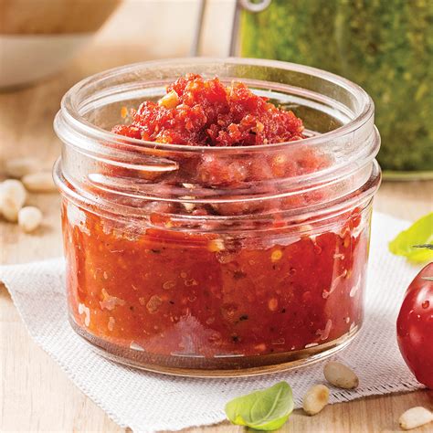 Gros plan sur un pesto de tomates séchées avec des feuilles de basilic frais et des copeaux de parmesan.