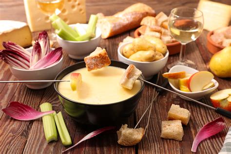 Table dressée avec une fondue au fromage et divers accompagnements