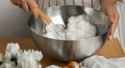 Un chef incorporant délicatement des blancs en neige dans une crème au mascarpone