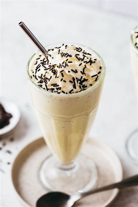 Verre de milkshake vanille garni de chantilly, vermicelles en chocolat et d'une paille