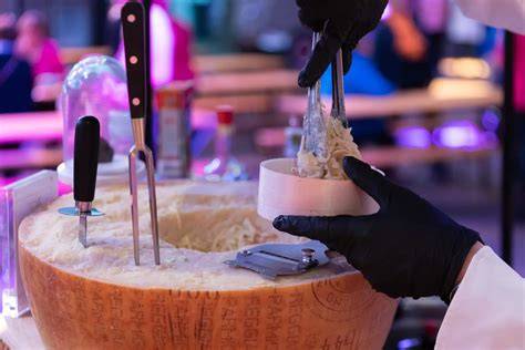 Imagerie montrant la meule de parmesan géante et les pâtes fumantes au service