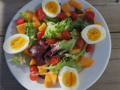 Salade mélangée avec melon, tomates noires et œufs pochés