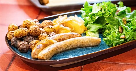 Une assiette de saucisses en cocotte servie avec une salade verte