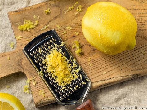 Un citron jaune coupé en deux, avec une râpe et du zeste