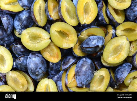 Vue aérienne d'une grande casserole remplie de prunes coupées en deux, prêtes à être cuites