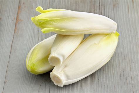 Endives crues coupées en deux dans une poêle