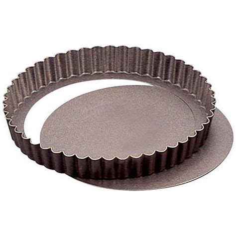 Gros plan sur un moule à tarte à fond amovible de 28 cm, vide, avec une pâte à tarte crue disposée à côté.