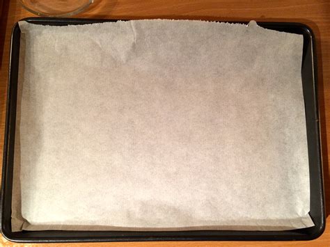 Saucisses fraîches disposées sur une plaque de cuisson recouverte de papier sulfurisé