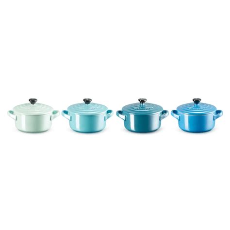 Une sélection de mini cocottes Le Creuset de différentes couleurs disposées sur une table