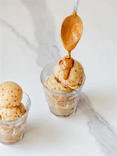 Vue rapprochée d'une cuillère versant de la sauce caramel sur de la crème fouettée, au sommet d'un Frappuccino