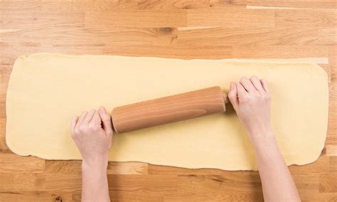 Un plan de travail avec de la farine, une pâte à beignets étalée et des emporte-pièces