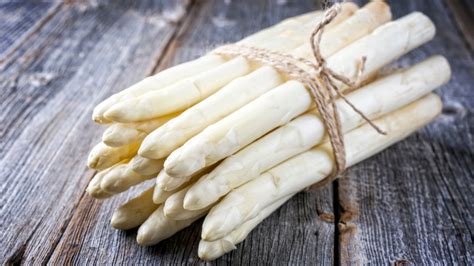Vue rapprochée d'un économe épluchant une asperge blanche