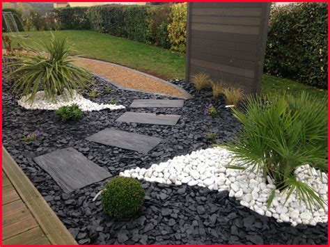 Allée de jardin bordée de galets noirs et de plantes vertes