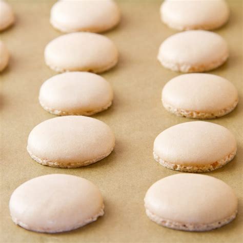 Une boîte hermétique contenant des coques de macarons séparées par du papier cuisson
