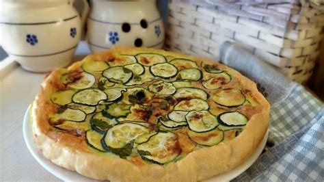 Un moule à tarte rempli de pâte brisée avec des courgettes et du chorizo coupés