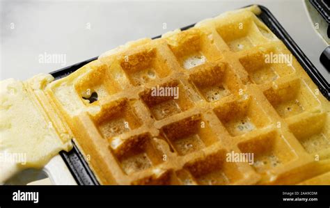 Gaufrier ouvert montrant une gaufre en cuisson