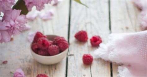 Framboises et pralines roses disposées sur un fond blanc