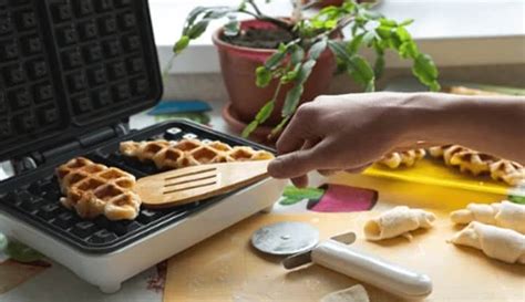 Mains nettoyant des plaques de gaufrier avec une spatule en bois