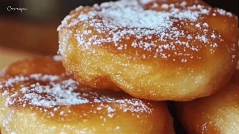 Des beignets dorés et moelleux, certains saupoudrés de sucre glace, d'autres avec une garniture visible.