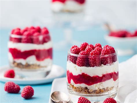 Une verrine de tiramisu framboise verveine avec des framboises fraîches et des feuilles de verveine en décoration