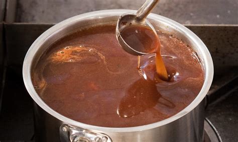Une louche de sauce brune versée sur un plat de viande
