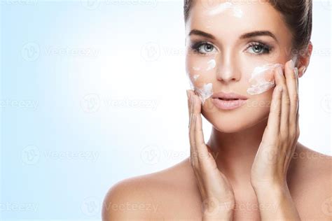 Une femme appliquant une crème hydratante sur son visage