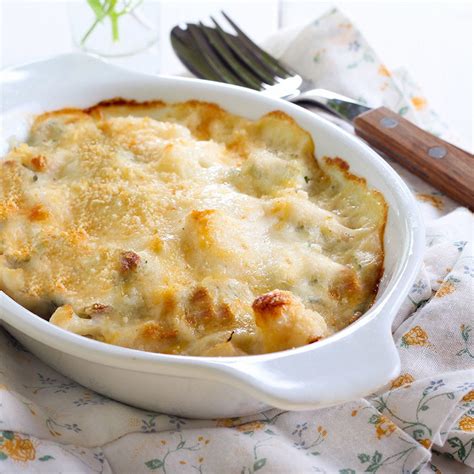 Un gratin de chou-fleur et pommes de terre au fromage à raclette dans un plat en terre cuite