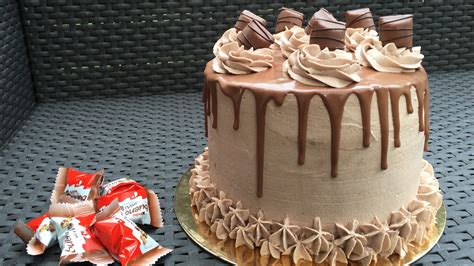 Un layer cake Kinder Bueno magnifiquement décoré avec des éclats de chocolat et des rosaces de crème