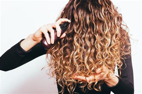 Femme aux cheveux bouclés utilisant un produit capillaire