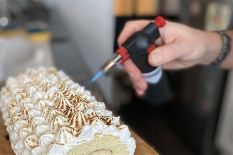 Un chalumeau de cuisine en action sur une meringue